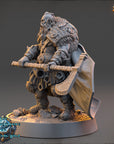 A detailed 3D model of a fantasy character, likely a dwarf or elf, holding a large weapon and standing on a rocky surface. The character has a long beard and is wearing a heavily decorated outfit with intricate patterns and designs.