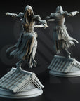 two statues of a woman in a flowing robe, one standing on a rooftop and the other on a pedestal.