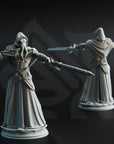 two detailed figurines of medieval-style characters, each holding a sword and wearing ornate robes.